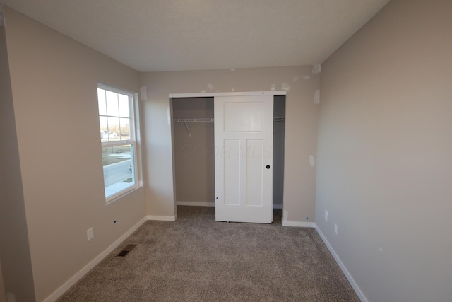 unfurnished bedroom featuring a closet, baseboards, visible vents, and carpet flooring