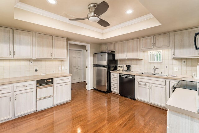 82 Bishop Sq, Columbus, OH 43209 - kitchen featuring black dishwasher, a tray ceiling, freestanding refrigerator, crown molding, and light wood-style flooring