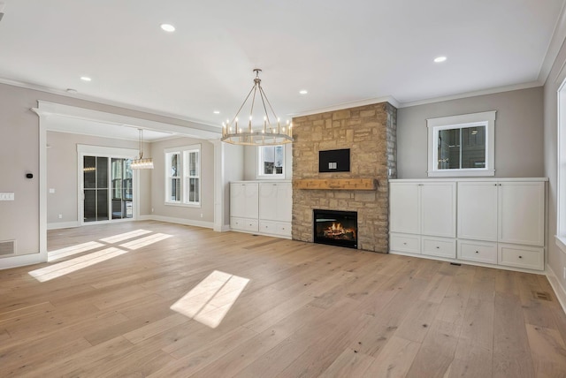 unfurnished living room featuring light wood-type flooring, ornamental molding, a chandelier, and a fireplace