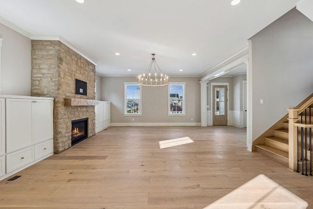 unfurnished living room with a stone fireplace, crown molding, a notable chandelier, and light hardwood / wood-style flooring