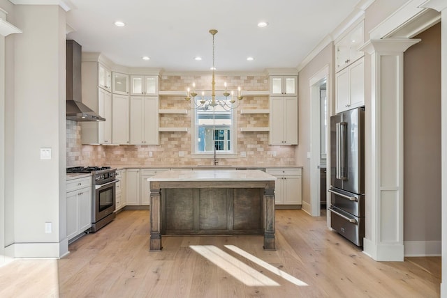 kitchen with white cabinetry, hanging light fixtures, wall chimney range hood, high end appliances, and sink