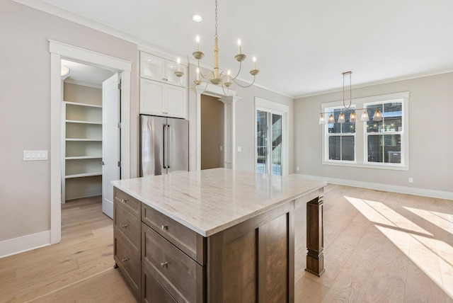 kitchen featuring a notable chandelier, decorative light fixtures, white cabinets, and high quality fridge