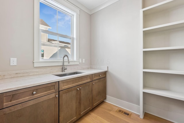 interior space featuring sink, crown molding, and light hardwood / wood-style flooring