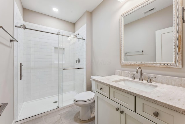 bathroom featuring tile patterned floors, toilet, vanity, and walk in shower