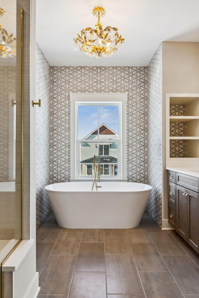 bathroom with an inviting chandelier, a bathtub, and vanity