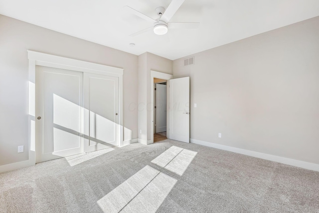 unfurnished bedroom with ceiling fan, light colored carpet, and a closet