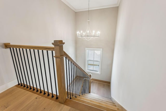 stairs with wood-type flooring, crown molding, and a chandelier