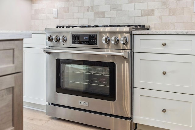 details featuring white cabinetry, light hardwood / wood-style floors, backsplash, gas range, and light stone countertops