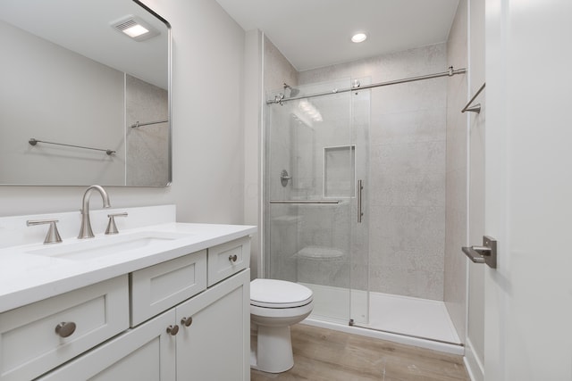 bathroom with toilet, vanity, a shower with shower door, and hardwood / wood-style floors