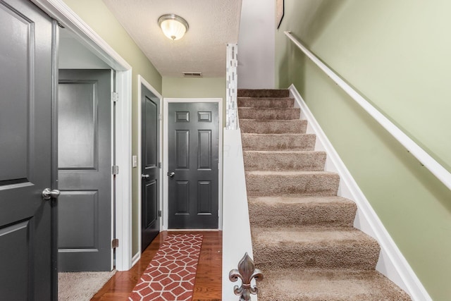 stairway featuring a textured ceiling and hardwood / wood-style floors