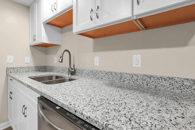 kitchen featuring white cabinets, light stone counters, stainless steel dishwasher, and sink