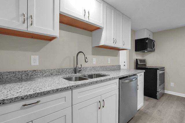 kitchen featuring sink, light hardwood / wood-style flooring, light stone countertops, appliances with stainless steel finishes, and white cabinetry