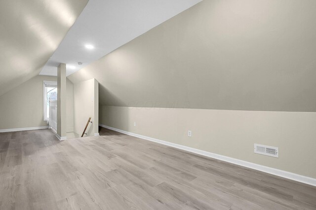 additional living space with light hardwood / wood-style floors and vaulted ceiling