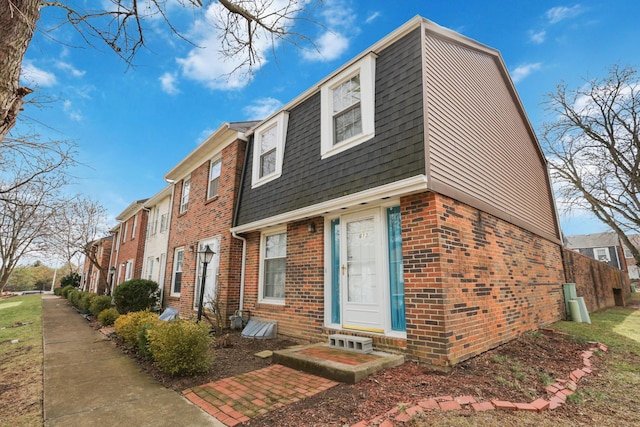 view of front of house featuring entry steps, brick siding, roof with shingles, and a residential view