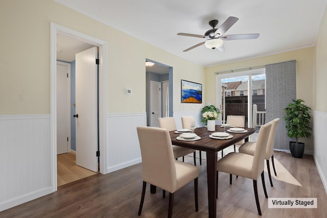 dining space featuring ceiling fan, wainscoting, wood finished floors, and crown molding