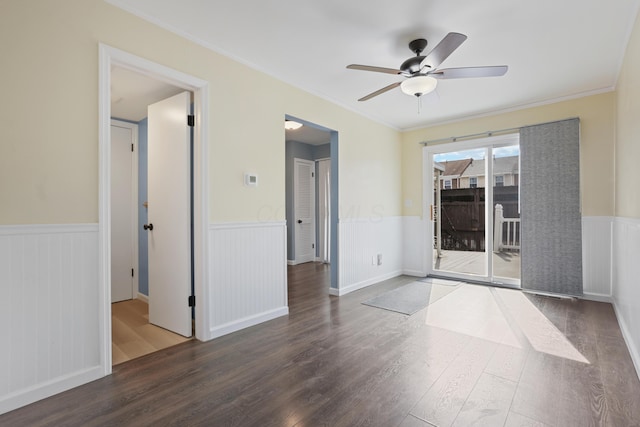 spare room featuring ceiling fan, crown molding, wood finished floors, and wainscoting