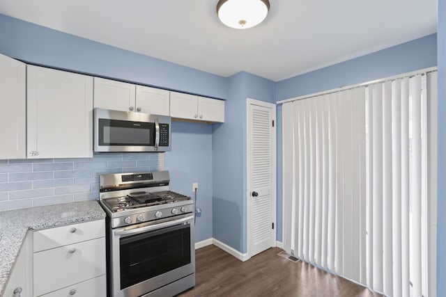 kitchen with stainless steel appliances, visible vents, backsplash, dark wood-type flooring, and white cabinetry