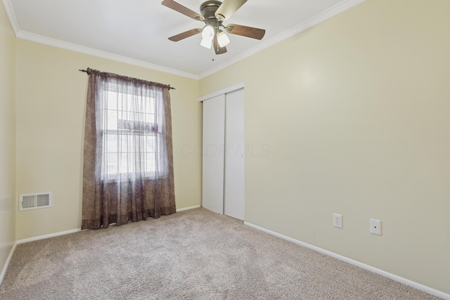 unfurnished bedroom featuring ornamental molding, a closet, visible vents, and carpet flooring