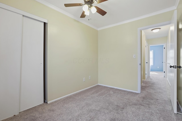 unfurnished bedroom featuring carpet floors, crown molding, baseboards, and a ceiling fan