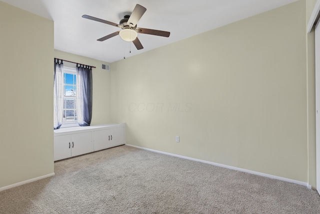 carpeted empty room featuring a ceiling fan, visible vents, and baseboards