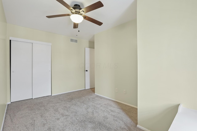 unfurnished bedroom with a closet, visible vents, a ceiling fan, carpet flooring, and baseboards