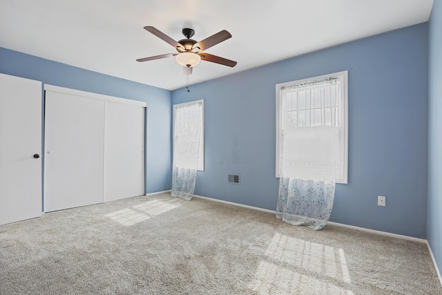 unfurnished bedroom featuring a ceiling fan, baseboards, a closet, and carpet flooring