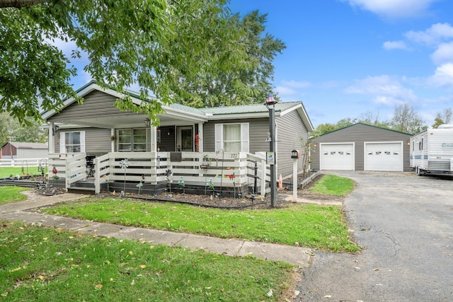 view of front of home with an outbuilding, a front lawn, covered porch, and a garage