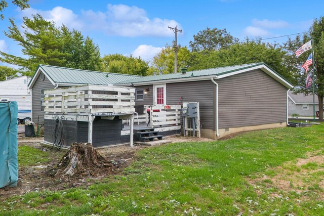 back of house featuring a lawn and a wooden deck