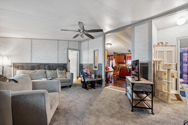 living room with ceiling fan, dark carpet, a textured ceiling, and brick wall