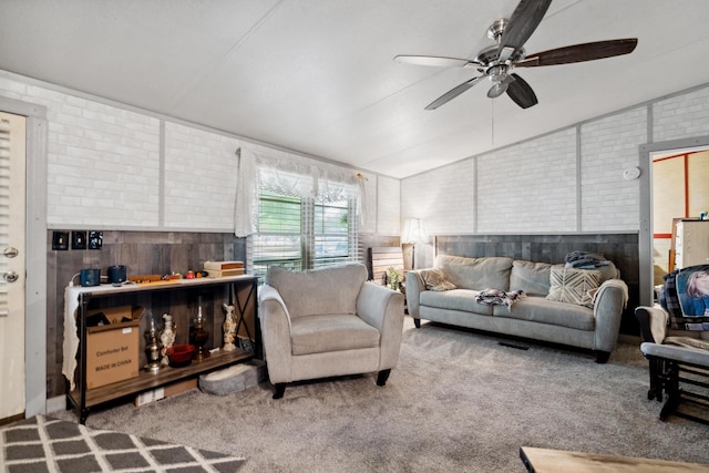 carpeted living room featuring wooden walls, ceiling fan, lofted ceiling, and brick wall