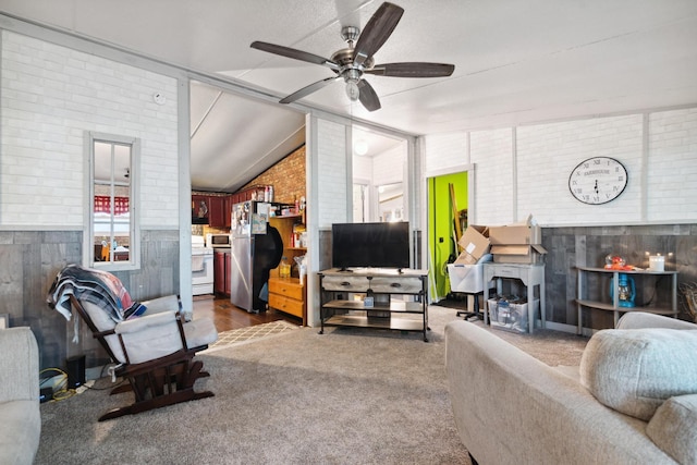 living room featuring ceiling fan, lofted ceiling, and brick wall