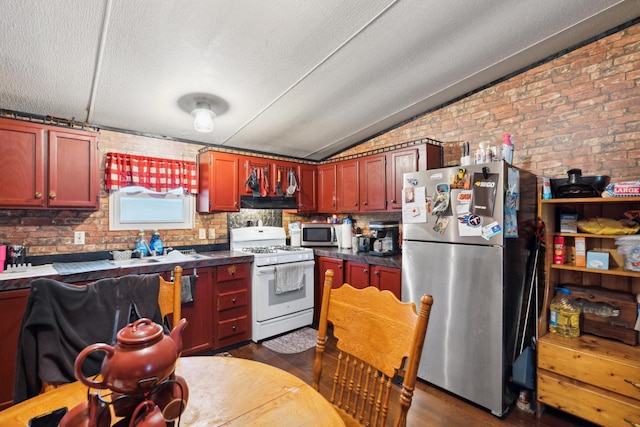 kitchen with dark hardwood / wood-style floors, brick wall, stainless steel appliances, and vaulted ceiling