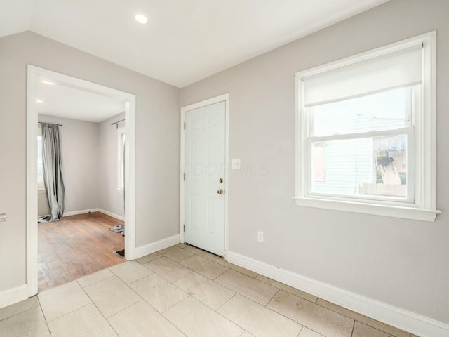 tiled spare room featuring vaulted ceiling