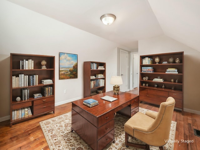 home office featuring light hardwood / wood-style floors and lofted ceiling