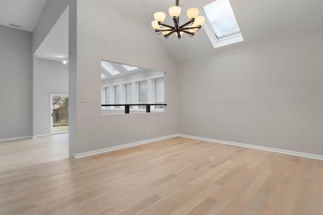 unfurnished living room with a skylight, high vaulted ceiling, a chandelier, and light hardwood / wood-style floors