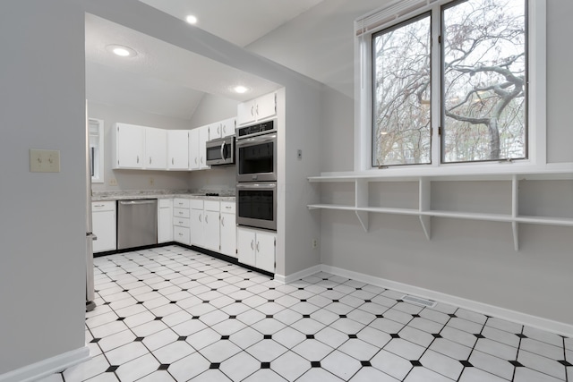 kitchen featuring white cabinets, appliances with stainless steel finishes, and vaulted ceiling