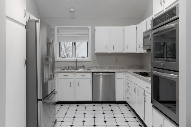 kitchen with white cabinetry, sink, stainless steel appliances, and vaulted ceiling