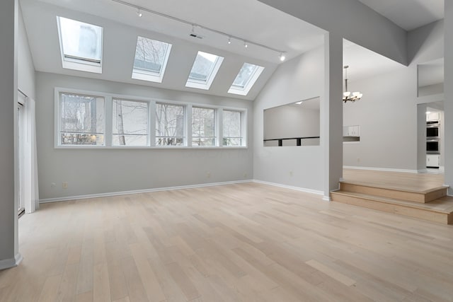 unfurnished living room featuring a chandelier, rail lighting, and light hardwood / wood-style floors