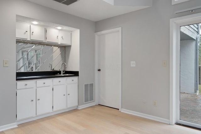 kitchen with light wood-type flooring, white cabinetry, sink, and tasteful backsplash