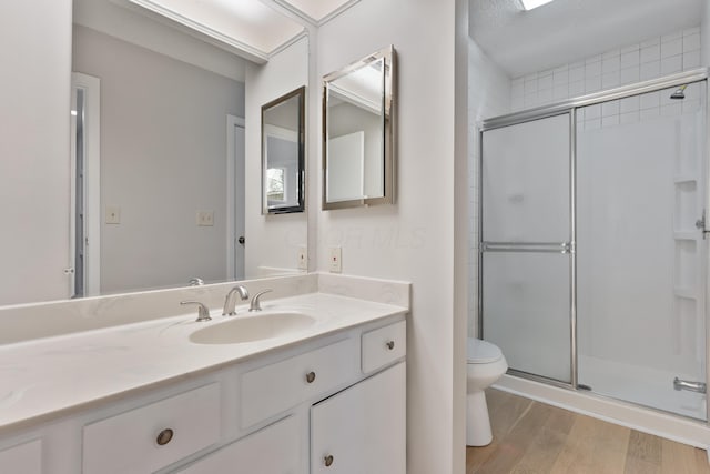 bathroom featuring hardwood / wood-style flooring, vanity, toilet, and a shower with door