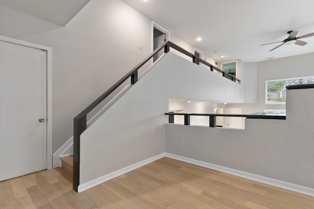 stairs featuring ceiling fan and hardwood / wood-style flooring