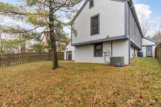 back of property featuring a yard and central AC