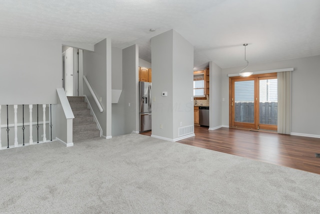 unfurnished living room featuring a textured ceiling and dark carpet