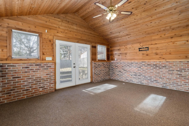 unfurnished room featuring french doors, brick wall, ceiling fan, wooden ceiling, and carpet floors