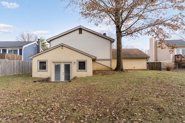 rear view of house with a lawn and french doors