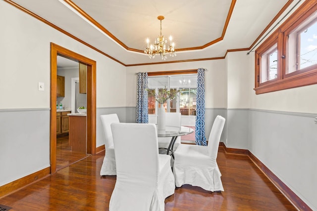 dining room with a raised ceiling, a notable chandelier, dark hardwood / wood-style flooring, and crown molding