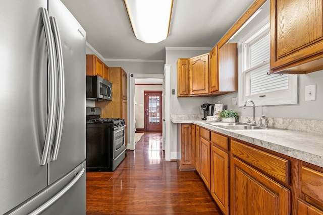 kitchen featuring sink, dark hardwood / wood-style flooring, ornamental molding, and appliances with stainless steel finishes