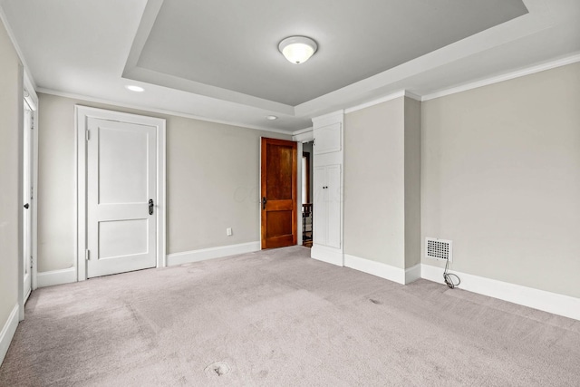 carpeted empty room featuring a tray ceiling and crown molding