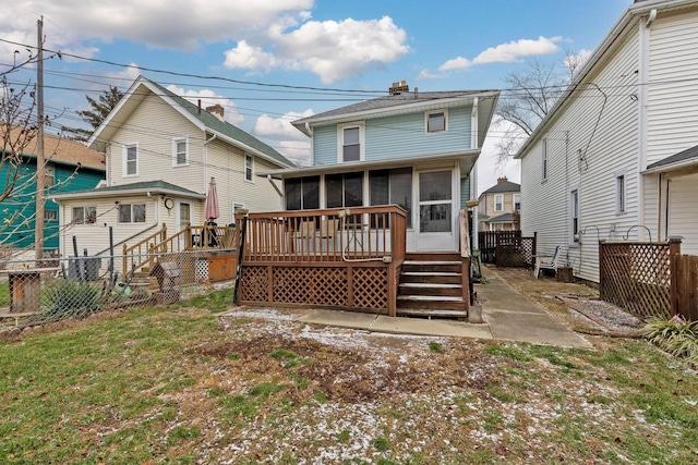 rear view of house featuring a lawn, a sunroom, and a wooden deck