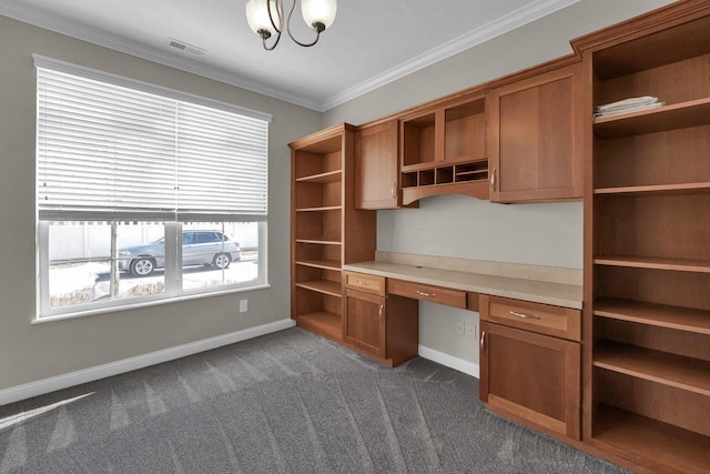 unfurnished office featuring dark colored carpet, crown molding, and built in desk